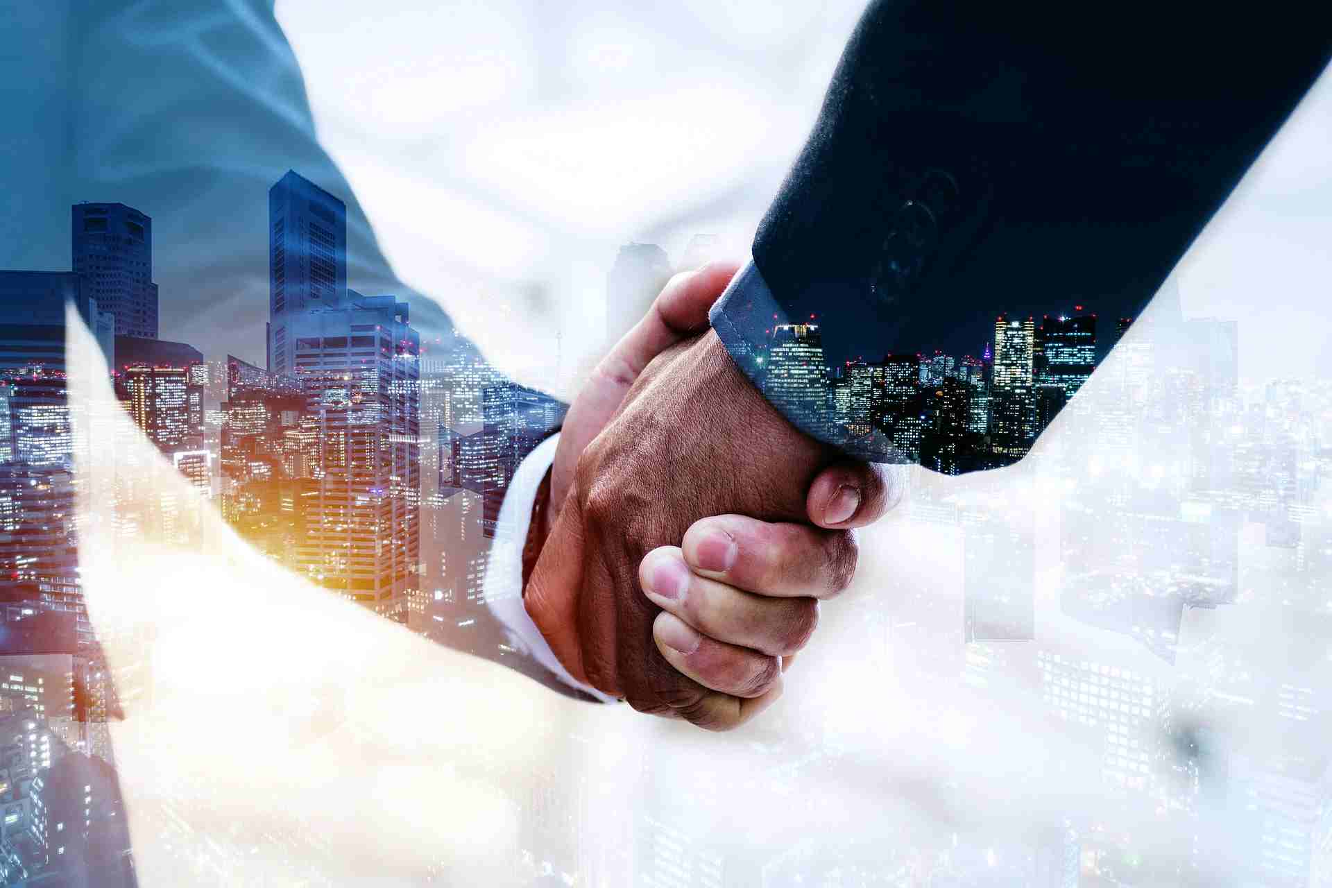 Businessmen shaking hands over cityscape, representing NBFC software partnership and financial
                           technology collaboration
