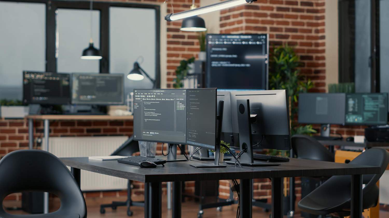 UModern office setup with multiple screens displaying code for developing cooperative society software 