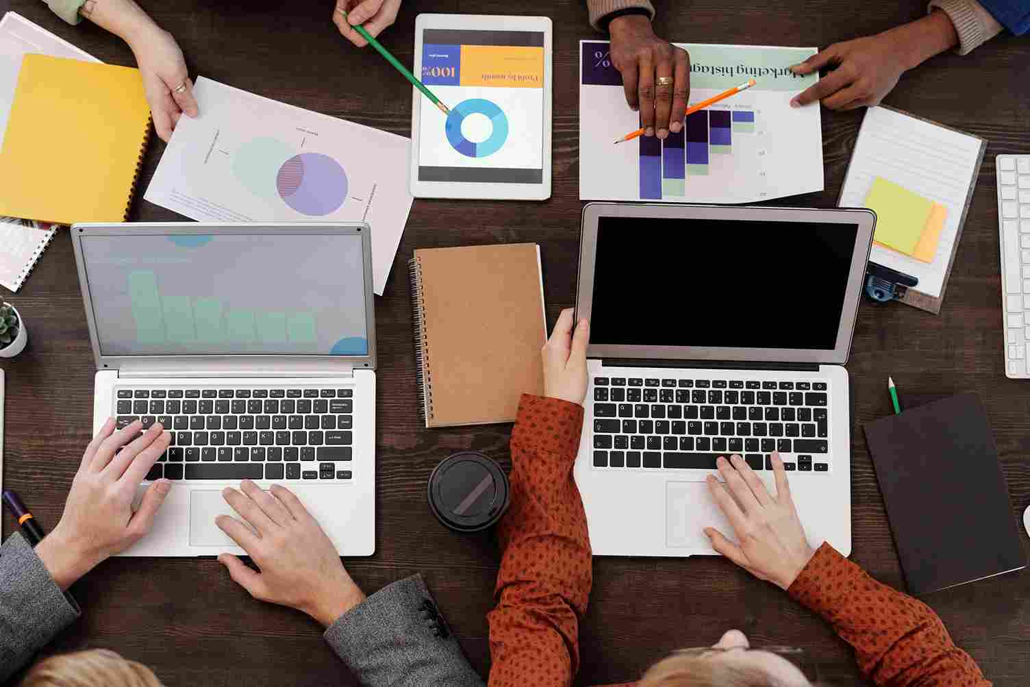Team analyzing charts and data on laptops and tablets during a strategy meeting for digital marketing services in Dehradun.