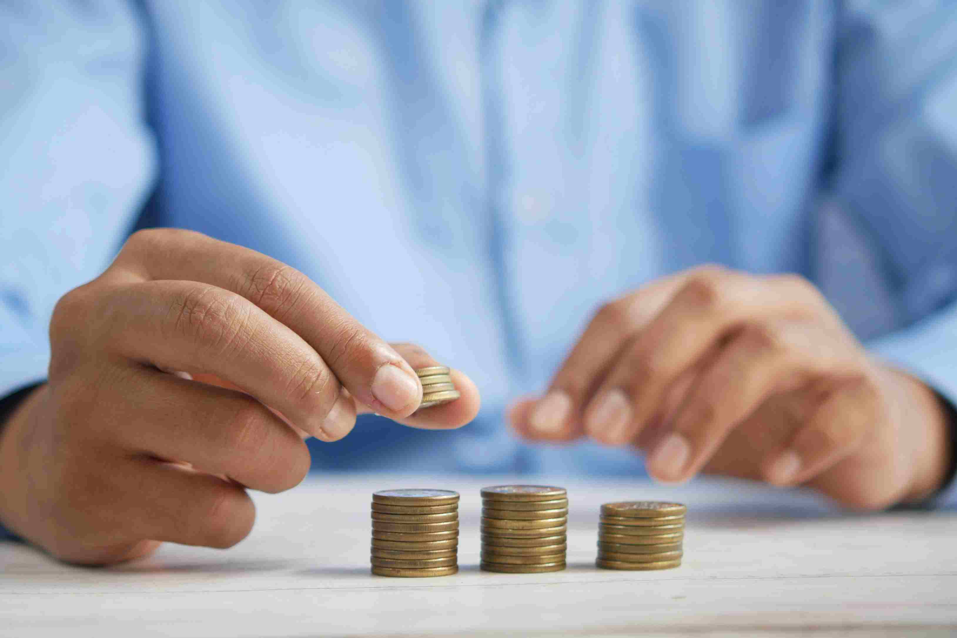 Person stacking coins symbolizing financial planning and savings, representing loan management
                           software for NBFCs