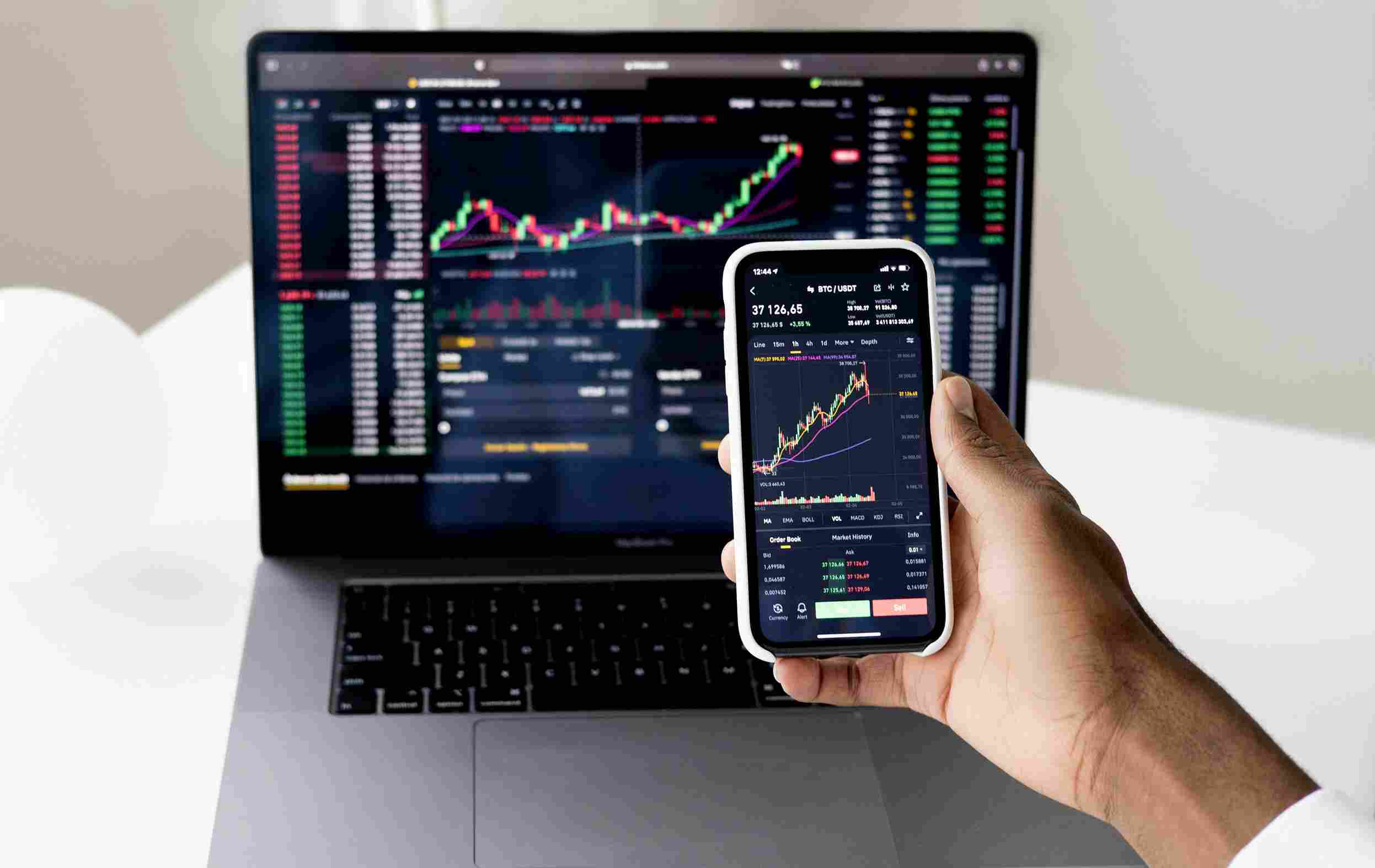 NBFC software development company dashboard showing financial analytics and trading data on laptop and smartphone