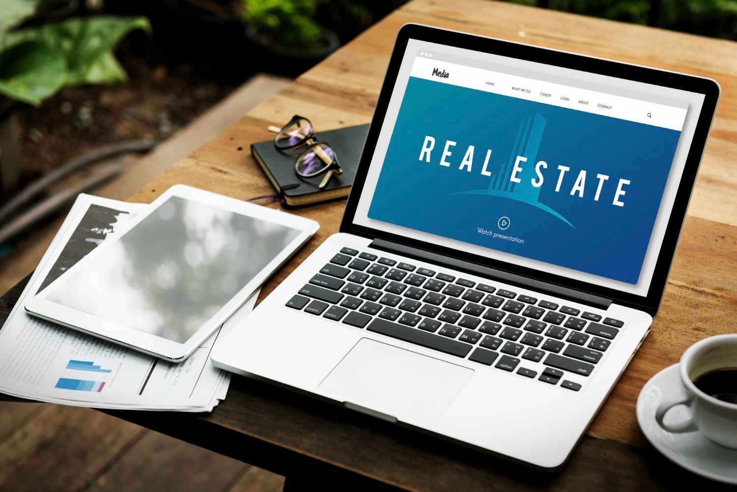 real-estate-crm-software dashboard on laptop screen with tablet, documents, and coffee on
wooden desk
